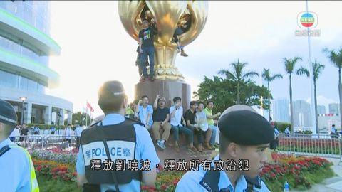 有示威者爬上金紫荊雕塑掛上橫額 拒絕離開被警包圍